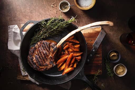 https://www.mychicagosteak.com/steak-university/wp-content/uploads/2021/12/cooked-tomahawk-steak-in-cast-iron-skillet-1.jpg